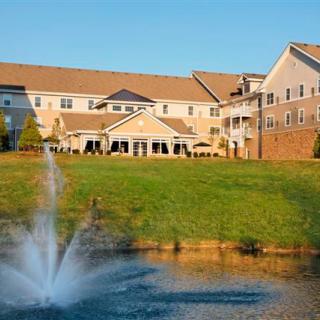 A large residential building with a pond and fountain in the foreground.