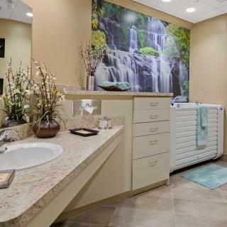 Modern bathroom with a sink, bathtub, and a large waterfall artwork on the wall.