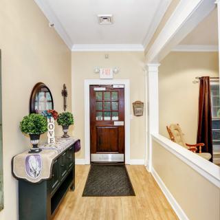 A welcoming entrance hallway decorated with greenery and a mirror, leading to a wooden door.