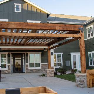 A modern residential building featuring a wooden pergola in its front yard.