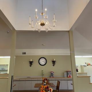 A well-decorated dining area featuring a chandelier, a wall clock, and mirrored walls.