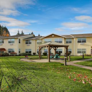 Sunny day view of a residential building with a garden and lawn.