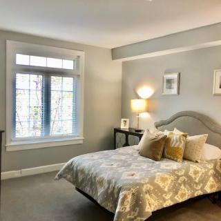 A cozy bedroom with a large window and neutral-toned decor.