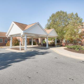 A building entrance with a covered driveway surrounded by trees.