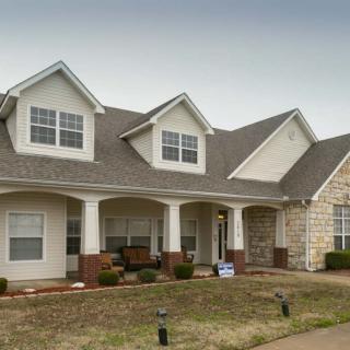 A two-story suburban house with a porch and brick features.