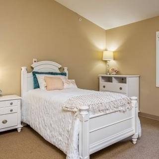 A cozy bedroom with a white bed, bedside lamp, and matching furniture.