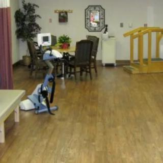 A rehabilitation room with exercise equipment and a hardwood floor.