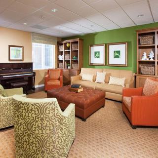 A cozy living room with colorful furniture, a piano, and a bookshelf.