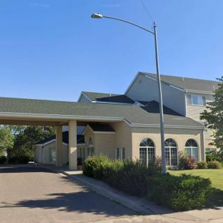 A hotel building with a covered driveway entrance and landscaped surroundings.
