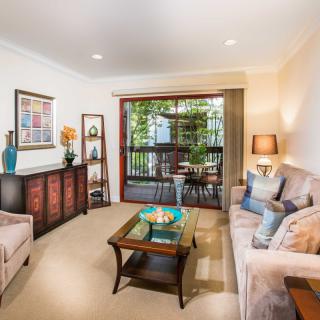 A cozy and well-decorated living room with comfortable seating, vibrant artwork, and ample lighting.
