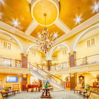 A luxurious hotel lobby featuring a grand staircase and an elegant chandelier.