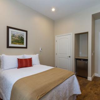 A cozy bedroom with a neatly made bed and wall art.
