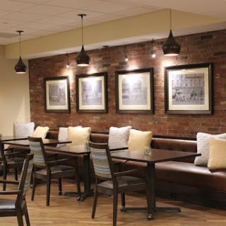 A cozy dining area featuring comfortable seating, elegant lighting, and a stylish brick wall.