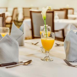 A formal dining table setting with orange juice and elegant decorations.