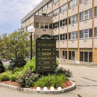 A well-maintained commercial building featuring a prominent entrance sign and landscaped surroundings.