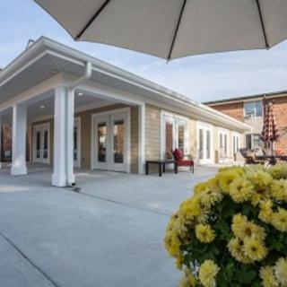 A patio area with a building in the background, featuring flowers and an umbrella.