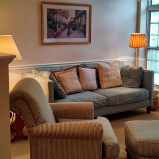 A cozy living room with a sofa, armchair, cushions, and ambient lighting.
