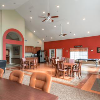 A spacious and well-lit interior with dining tables, ceiling fans, and a kitchen area.