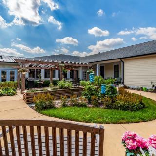 A beautiful courtyard garden with pathways, vibrant flowers, and a pergola under a clear blue sky.