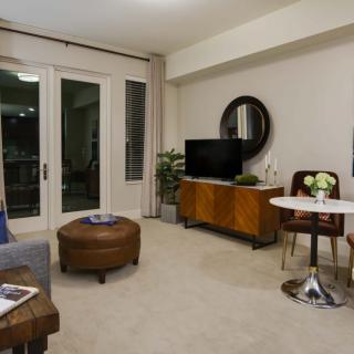 A cozy living room with modern decor, featuring a TV, sofa, small table and chairs, and accent pieces.