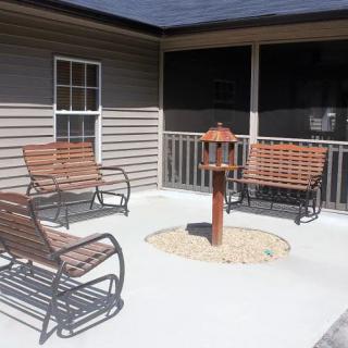 A cozy patio area featuring wooden rocking benches and a bird feeder.