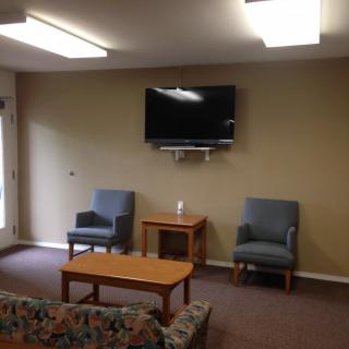 A cozy living room setup featuring a wall-mounted television, two chairs, and a coffee table.