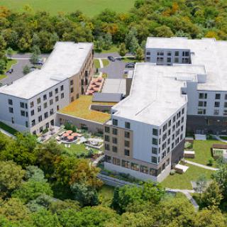 Aerial view of a modern architectural complex surrounded by lush greenery.