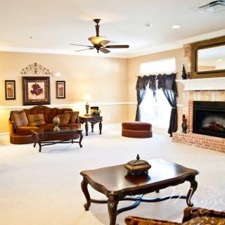 A spacious and elegantly decorated living room featuring a sofa, coffee table, fireplace, and ceiling fan.