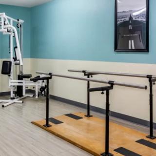 A physical therapy room equipped with parallel bars and exercise equipment for rehabilitation.
