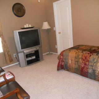 A cozy bedroom featuring a television, bed, and floor lamp.
