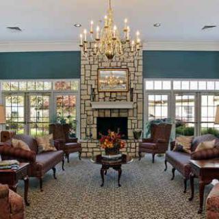 A luxurious living room with classic furniture, a chandelier, and a fireplace.
