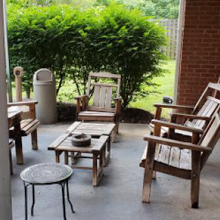 A cozy outdoor seating area featuring wooden furniture surrounded by greenery.