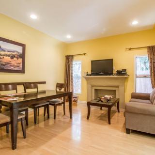 A cozy living room with yellow walls featuring a dining area, fireplace, and television.
