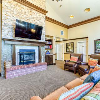 A cozy living room with a stone fireplace, mounted TV, and comfortable seating.