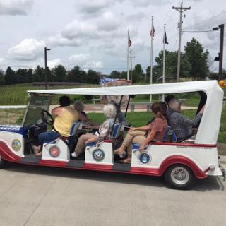 A group enjoying a ride in a colorful tourist cart on a sunny day.