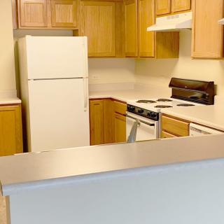 A kitchen with wooden cabinets, a white fridge, and an electric stove.