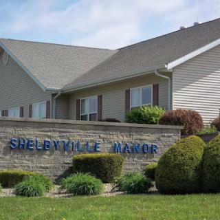 Shelbyville Manor sign in front of a residential building with landscaped surroundings.