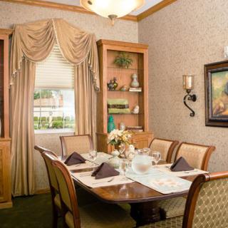 A cozy dining room with a neatly set table, elegant curtains, and tasteful decor.