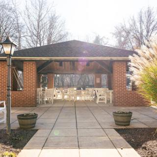A welcoming outdoor patio with seating surrounded by lush greenery, basking in sunlight.