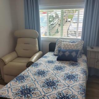 A cozy bedroom with a patterned bedspread and a comfortable recliner by the window.