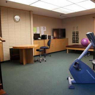 An office space with exercise equipment, including a stationary bike and an exercise ball.