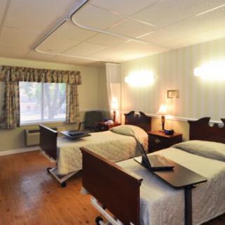 A nursing home room with two beds and warm lighting.