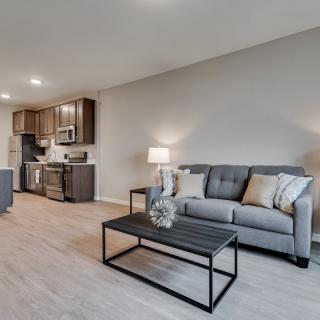 A modern living room with an open floor plan featuring a comfortable sofa and sleek coffee table adjacent to a contemporary kitchen area.