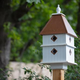 A decorative birdhouse in a garden setting.