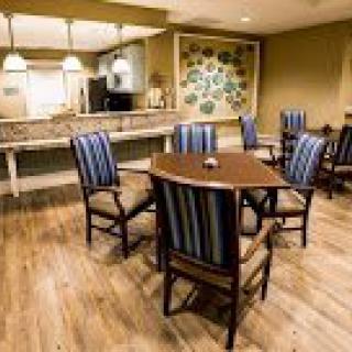 A cozy dining area with a modern design, featuring wooden floors and striped upholstered chairs.