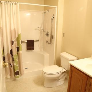 A modern bathroom features a shower with a curtain, toilet, and sink.