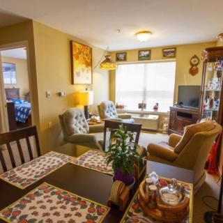 A cozy living and dining area with comfortable seating, decorative elements, and natural light from a large window.