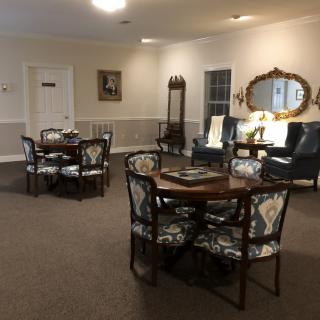 A cozy lounge area with tables, chairs, and a decorative mirror.