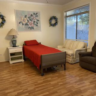 A cozy bedroom featuring a red bedspread, comfortable seating, and charming decorative elements.