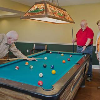 Three men enjoying a game of pool in a game room.